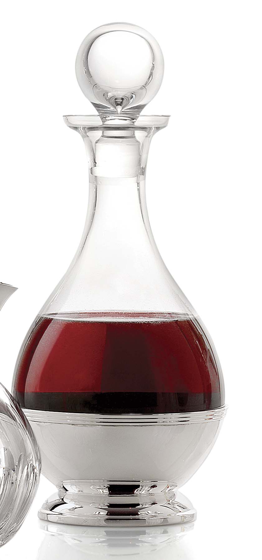LEAD CRYSTAL GLASS DECANTER WITH A ROUND BASE. IT HAS A LEAD CRYSTAL GLASS STOPPER. IT HAS A STAND (OR BASE) MADE OF STERLING SILVER. THIS BASE PERMITS THE DECANTER TO BE PLACED ON A SURFACE IN AN UPRIGHT POSITION; IT IS NOT PERMANENTLY ATTACHED TO THE DECANTER. AS SUCH IT IS A FUNCTIONAL PART OF THE DECANTER. THE LEAD CRYSTAL IS GATHERED BY HAND.
