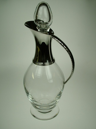 LEAD CRYSTAL GLASS JUG WITH A STERLING SILVER SPOUT AND HANDLE. THE SILVER IS AN INTERGRAL PART OF THE JUST USED TO HELP POUR THE LIQUID AND HOLD THE JUG. IT CANNOT BE REMOVED. WITH LEAD CRYSTAL GLASS STOPPER. THE LEAD CRYSTAL IS GATHERED BY HAND.