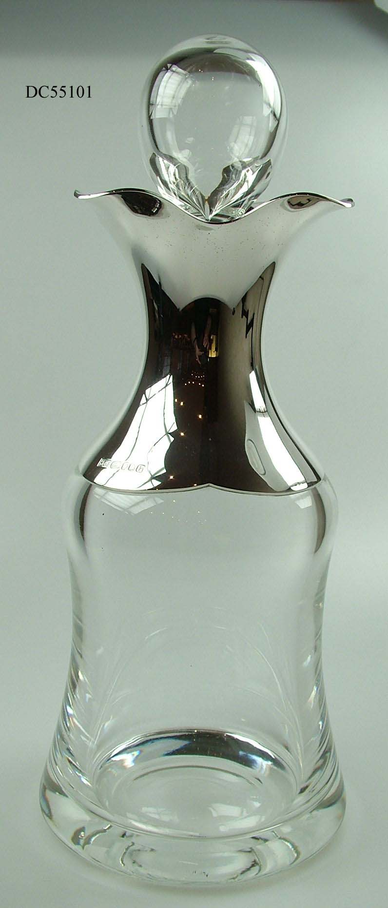 LEAD CRYSTAL GLASS DECANTER WITH A LEAD CRYSTAL GLASS STOPPER. THE NECK IS COVERED IN STERLING SILVER WHICH FORMS A FUNCTIONAL SPOUT. IT IS FIXED TO THE CRYSTAL AS AN INTEGRAL PART AND IS NOT INTENDED TO BE REMOVED. THE LEAD CRYSTAL IS GATHERED BY HAND.
