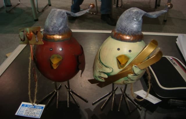 A SET OF TWO TIN ROBINS IN FESTIVE ATTIRE. THE ROBINS ARE WEARING PURPLE FATHER CHRISTMAS STYLE HATS.ONE ROBIN HOLDS A SIGN SAYING JOY, THE OTHER HOLDS A PAIR OF SKIS. THE BODY  OF THE BIRDS ARE MADE OF TIN WITH STEEL WIRE FEET. ONE BIRD IS COLOURED RED AND THE OTHER CREAM.PACKAGED TOGETHER FOR RETAIL SALE IN A CARDBOARD BOX.