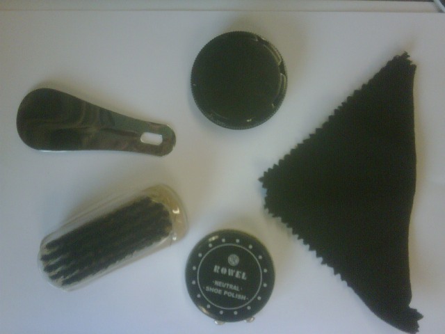 BOOT CARE KIT CONTAINER MADE OF SYNTHETIC FAKE LEATHER, HOLDING A SMALL BRUSH, BOOT POLISH, SPONGE, NYLON CLOTH AND STEEL SHOE HORN. ALL PRODUCTS FOR CLEANING BOOTS.