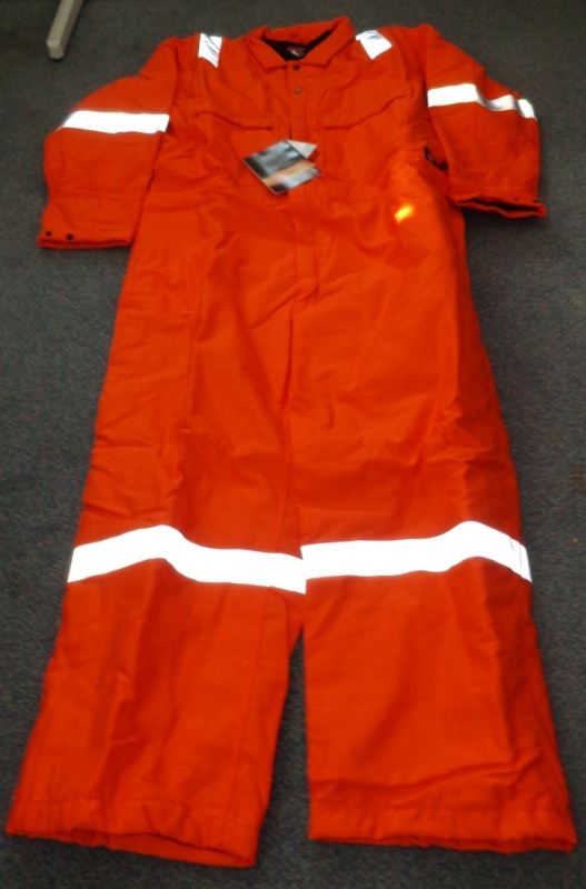 A HEAVY WOVEN COVERALL OF 100% COTTON EXTERIOR AND POLYESTER INSULATION. IT IS A FLAME RESISTANT ARTICLE FOR USE IN WORKING ENVIRONMENTS WHERE EXPOSURE TO HIGH HEAT OR FLAMES MAY OCCUR.
IT HAS A CENTRAL ZIP FROM THE CHEST DOWN TO THE TOPS OF THE LEGS, COVERED WITH A LEFT OVER RIGHT FLAP AND WITH TWO PRESS STUDS ABOVE THE ZIP AT THE TOP. THERE ARE TWO BREAST POCKETS, EACH CLOSING WITH A ZIP, AND A SMALL POCKET ON THE LEFT ARM CLOSING WITH A PRESS STUD. THE REAR OF THE LOWER BACK HAS TWO POCKETS, EACH WITH A FLAP BUT NO CLOSING MECHANISM.
IT IS BRIGHT ORANGE IN COLOUR WITH SILVER REFLECTING STRIPS ON THE LEGS, ARMS AND SHOULDERS. ENCLOSED IN A PLASTIC BAG.
