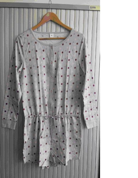 ALL IN ONE GARMENT OF COTTON. REACHING FROM THE SHOULDERS DOWN TO THE UPPER THIGH IN LENGTH ENVELOPING EACH LEG SEPARATELY IN THE STYLE OF SHORTS. A KNITTED GARMENT WITH BUTTON FASTENING RIGHT OVER LEFT FROM THE NECKLINE TO THE WAIST. ROUND NECK AND LONG SLEEVES WITH TIGHTENING AT THE CUFFS. WITH A DRAWSTRING TIE AT THE WAIST. HEMMED AT THE BASE OF THE SHORTS. LIGHT GREY IN COLOUR WITH COLOURED SPOTS.