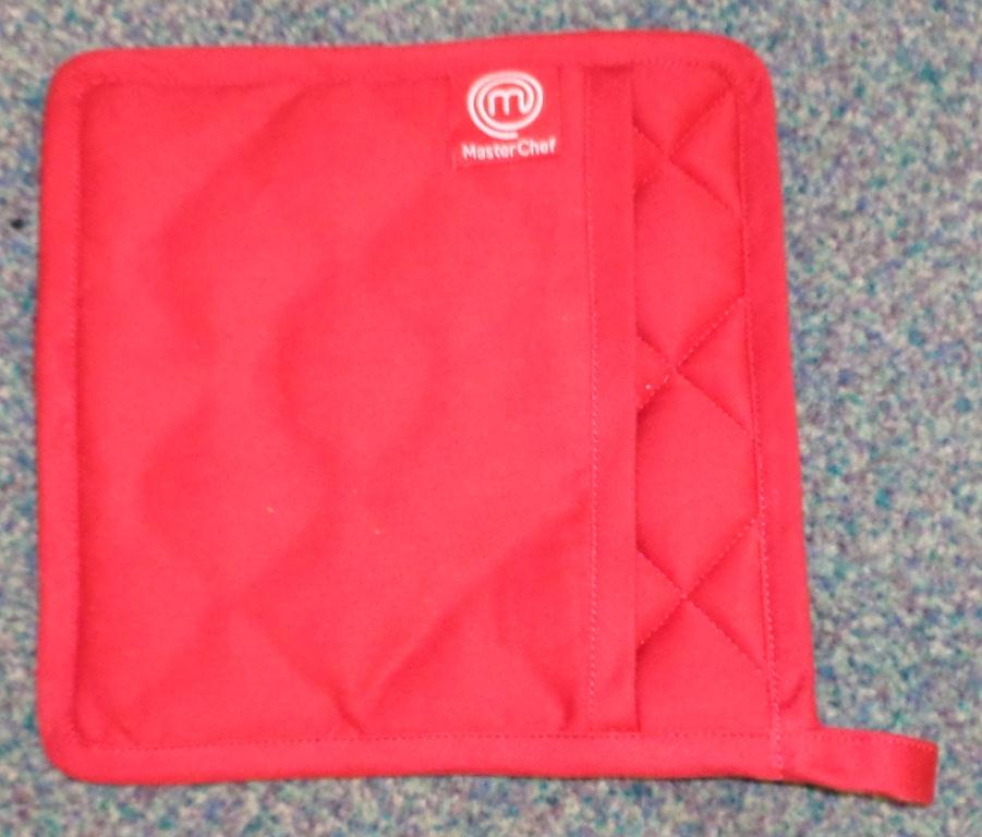 A COOKING POT HOLDER OF 100% COTTON. IT IS SQUARE, MEASURING 20 CENTIMETRES ON EACH SIDE. IT IS PADDED, WITH AN ADDITIONAL NON PADDED COVERING ON ONE SIDE TO ENABLE A HAND TO BE INSERTED. HAS A LOOP ON ONE CORNER FOR HANGING IT. RED IN COLOUR.