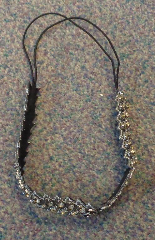 A CIRCULAR HAIRBAND DESIGNED FOR WOMEN. THE BAND IS MADE FROM A STRIP CONSISTING OF  60% FELT AND ANOTHER STRIP JOINED TO THE FELT OF 40% ELASTIC.  THE FELT HAS ACRYLIC BEADS SEWN ALONG ITS LENGTH FOR DECORATIVE EFFECT. THE ELASTIC BAND IS COVERED WITH TEXTILE AND IS DOUBLED FOR EXTRA STRENGTH.