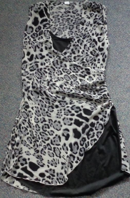 PRINTED WRAP TUNIC TOP : DOUBLE LAYERED UPPER GARMENT FOR OUTER WEAR. OUTER LAYER OF SHEER WOVEN POLYESTER, INNER LAYER ON FRONT ONLY, OF KNITTED POLYESTER. GARMENT IS SLEEVELESS, WITH A SCOOP NECKLINE AND WRAP OVER DETAIL AT FRONT. GARMENT REACHES FROM SHOULDER TO 4 INCHES ABOVE THE KNEE. TO BE WORN WITH TROUSERS/LEGGINGS. MEASUREMENT FROM CENTER OF NECKLINE TO CENTER OF CURVED HEM IS 39 CENTIMETRES, THEREFORE CLASSIFIED AS A DRESS.