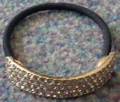 CALISTA TEXTILE COVERED ELASTIC HAIRBAND TO HOLD HAIR IN A PONY TAIL STYLE, WITH METAL AND GLASS FEATURE. THE TEXTILE HAS THE APPEARANCE OF BEING KNITTED.