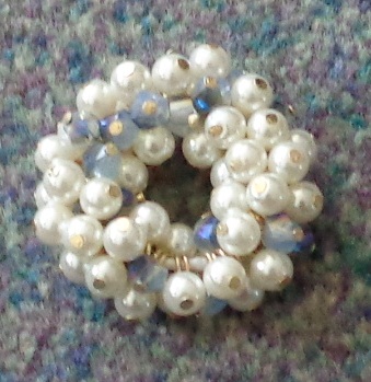 AMBER PONY TAIL HAIR BAND MADE FROM ELASTIC WITH TEXTILE OUTER AND COVERED IN PLASTIC BEADS. USED TO HOLD HAIR IN A PONY TAIL HAIR STYLE. THE TEXTILE OUTER HAS THE APPEARANCE OF BEING KNITTED.