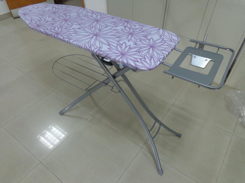 A FOLDING IRONING BOARD, OF POWDER COATED MILD STEEL TUBE CONSTRUCTION.  THE IRONING BOARD INCLUDES AN IRON REST AND LAUNDRY RACK. THE TOP OF THE IRONING BOARD IS COVERED WITH COTTON COVERED FOAM.  SURFACE DIMENSIONS: 38 X 122 CM.