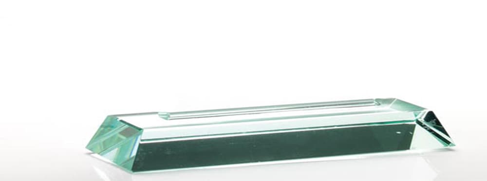 A GLASS TROPHY BASE MADE FROM CAST GLASS. THE ITEM HAS BEEN SHAPED AND EDGE WORKED BUT IS UNFINISHED IN ITS PRESENT FORM. THE TOP HAS A RECESS TO ACCEPT A TROPHY BLANK WHICH IS GLUED IN TO FORM THE FINISHED ARTICLE.