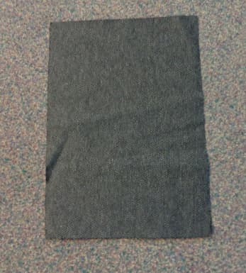 FABRIC CONSISTING OF A BLACK LAYER OF A RETICULATED POLYURETHANE FOAM  (CELLULAR PLASTIC) THAT HAS BEEN COATED THROUGHOUT WITH  ACTIVATED CARBON.
A  KNITTED POLYCOTTON TEXTILE HAS BEEN LAMINATED TO ONE  SIDE USING AN EVA ADHESIVE.

THE KNITTED  POLYCOTTON TEXTILE HAS A GREY AND BLACK PATTERNED  APPEARANCE CREATED BY A  COMBINATION OF DIFFERENT COLOUR YARNS USED IN THE FABRIC.  

THE FABRIC HAS A NOMINAL WEIGHT OF 300 GSM AND IS SUPPLIED ON A ROLL OF A NOMINAL WIDTH OF 1.5 METRES.

THE FABRIC IS USED IN THE MANUFACTURE OF UNIFORMS, WARFARE WEAR AND PROTECTIVE EQUIPMENT WITH THE INTENDED FUNCTION OF OFFERING CHEMICAL PROTECTION.