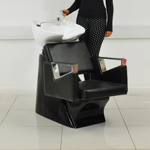 SALON WASH UNIT. THE PRODUCT COMPRISES OF A WOODEN CHAIR WHICH HAS BEEN UPHOLSTERED IN A FAUX STYLE LEATHER MATERIAL COLOURED BLACK. ATTACHED TO THE CHAIR IS A WHITE CERAMIC BASIN THAT IS MOUNTED ON A TILTING MECHANISM. THE PRODUCT COMES COMPLETE WITH WASTE PIPES AND MIXER TAP WITH HOT AND COLD WATER PIPES. INCLUDED WITH THE SINK BASIN IS A 50MM DIAMETER SHOWER HEAD, SINK AND WASTE BASKET. THE LEATHER FINISHED CHAIR HAS A CUSHIONED SEAT FOR EXTRA COMFORT AND SILVER CHROME EFFECT ARM RESTS WITH SOFT LEATHER STYLE PADS. INCLUDES FRONT/BACK TILTING MECHANISM FOR THE BASIN AND WIPE CLEAN SURFACE. THE CHAIR CAN BE USED WITH OR WITHOUT THE WASH FACILITY.
