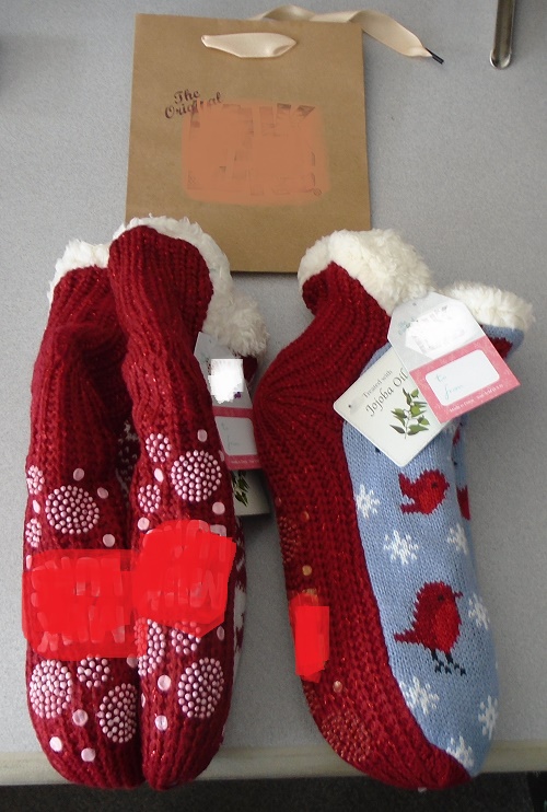 LADIES SLIPPER BOOTIES.  FOR INDOOR USE.  PULL ON SOCK STYLE WITH SPECIFICALLY SHAPED 'WELT' TOE AND HEEL SECTION.   KNITTED OUTER SHELL MADE FROM ACRYLIC, POLYESTER AND OTHER FIBRE.  SLIPPER BOOTIES HAVE DECORATIVE FRONT WITH PLAIN SPARKLE EFFECT BOTTOM.  LINING OF POLYESTER FAUX FUR.  SLIPPERS ARE NON-SLIP.  10 INDIVIDUAL DOTS, 6 SWIRL CIRCLES OF SMALLER DOTS AND COMPANY NAME IN RUBBER PROVIDE THE GRIP.  THE PREDOMINANT MATERIAL IN CONTACT WITH THE GROUND IS TEXTILE.  NOT CONSIDERED TO HAVE APPLIED SOLE.  LINING IS INFUSED WITH JOJOBA OIL.  EACH PACK CONTAINS TWO PAIRS OF SLIPPER BOOTIES, 1 GIFT TAG AND 1 GIFT BAG PACKAGED READY FOR RETAIL SALE.