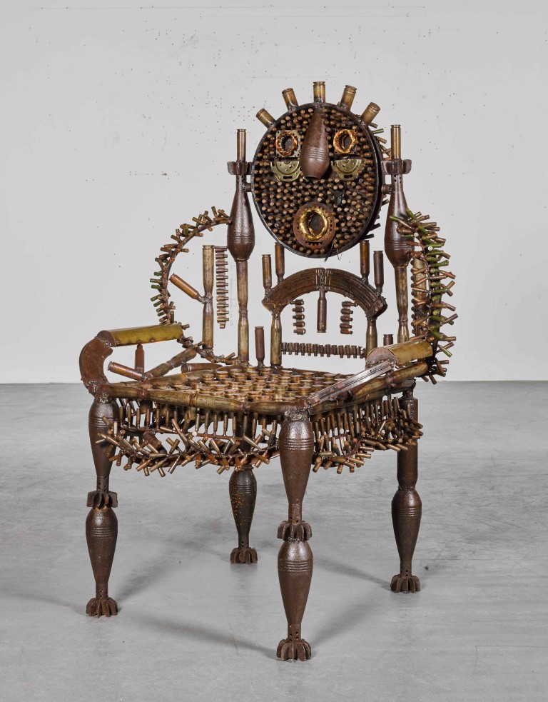 AN ORIGINAL SCULPTURE IN THE STYLE OF A THRONE BY GONÇALO MABUNDA. IT IS CALLED SUPREMACY. IT IS MADE FROM METAL AND RECYCLED WEAPONS COLLECTED AFTER THE MOZAMBIQUE CIVIL WAR WHICH WAS FOUGHT BETWEEN 1977 TO 1992. MEASUREMENTS ARE 147 CM X 100 CM X 92 CM.