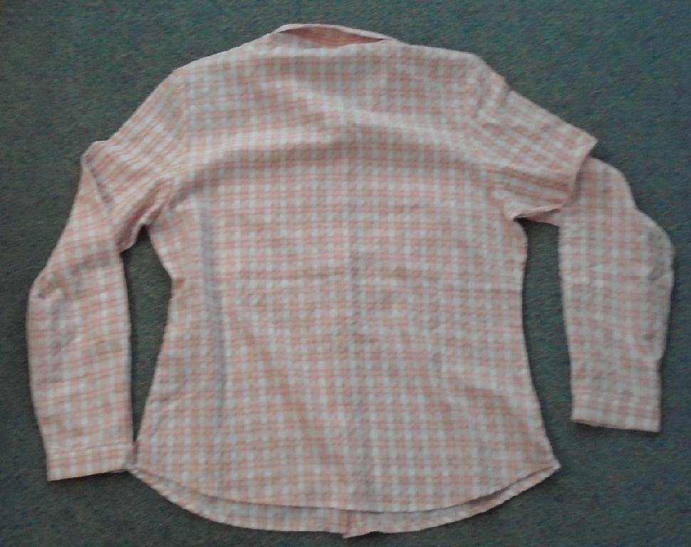 LADIES WOVEN LONG SLEEVE SHIRT.  MADE OF 83% POLYESTER AND 17% POLYAMIDE.  THE SHIRT FEATURES A LAPEL COLLAR WITH FULL FRONT OPENING THAT IS FASTENED BY INVISIBLE PRESS STUDS.  RIGHT OVER LEFT FASTENING (LADIES). WITH TWO BREAST POCKETS WITH VELCRO FASTENING, WITH A THIRD SECURITY ZIP UP POCKET AT THE WAIST.  THE LONG SLEEVES HAVE A CUFF SECURED BY TWO WHITE PRESS STUDS ON EACH SLEEVE, ALSO THE SLEEVES HAVE A TAG WITH A SINGLE PRESS STUD TO ALLOW THE SLEEVES TO BE WORN AT ELBOW LENGTH.  SHIRT IS PATTERNED IN A CHECK DESIGN IN PEACH AND WHITE.  

SHIRT IS SUPPLIED WITH MANUFACTURING TAGS FASTENED TO SIZE TAG WHICH IS SECURED INTO SHIRT AT THE COLLAR.  

PACKAGED IN PLASTIC BAG SHOWING THE COMPANY NAME READY FOR RETAIL SALE.
