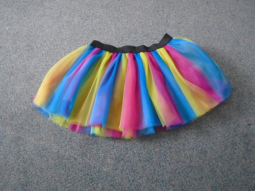 TUTU STYLE SKIRT WITH AN ELASTICATED WAISTBAND.  THE TUTU SKIRT IS MADE FROM 100% POLYESTER KNITTED MESH FABRIC.  THE SKIRT CONSISTS OF THREE LAYERS OF POLYESTER MESH    THE POLYESTER MESH IS YELLOW, PINK AND BLUE IN COLOUR WITH A BLACK ELASTIC WAISTBAND.  FOR UNISEX.  THE TUTU WOULD BE WORN OVER CLOTHES AND WOULD BE WORN FOR FANCY DRESS, CARNIVAL OR CHARITY FUN-RUN PURPOSES.