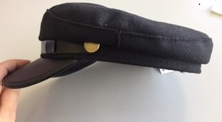 LADIES FASHION BAKER BOY STYLE HAT.  HAT IS MADE OF POLYESTER FELT WITH POLYURETHANE (PU) PEAK.  HAT AND PEAK ARE BLACK IN COLOUR.  DECORATIVE PLASTIC STRAP WITH DECORATIVE METAL STUD BUTTONS ABOVE THE PEAK OF THE HAT.  HAT IS LINED WITH TEXTILE MATERIAL.