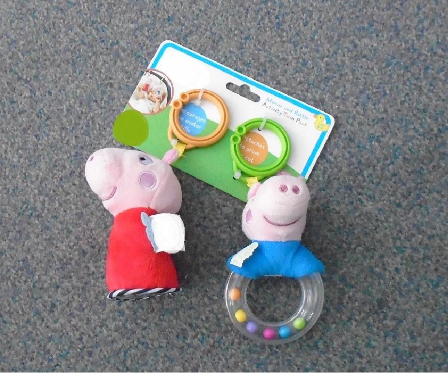 A PAIR OF WELL-KNOWN TV/BOOK CHARACTER'S IN THE FORM OF A PIG SOLD AS A MIRROR AND RATTLE ACTIVITY PACK. ONE PIG HAS A PINK HEAD WITH A RED BODY, ON THE BASE SIDE THERE IS A PLASTIC MIRROR. THE SECOND PIG HAS A PINK HEAD WITH A 1/4 BODY IN BLUE, THE REST OF THE BODY IS MADE OF A CLEAR PLASTIC RING WITH 6 BEADS INSIDE FORMING A RATTLE. BOTH PIGS ARE MADE OF A PLUSH TEXTILE MATERIAL AND THEN STUFFED WITH A FLEXIBLE MATERIAL. EACH HANGS FROM A PLASTIC RING THAT CAN BE ATTACHED TO A PRAM, COT OR CAR SEAT TO KEEP THE BABY AMUSED. SUITABLE FROM BIRTH. PACKAGED ON A BRIGHTLY COLOURED HANGING CARD.