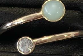 A LADIES ADJUSTABLE RING MADE FROM A BASE METAL OF BRASS WHICH IS PLATED WITH EITHER IMITATION GOLD, ROSEGOLD OR SILVER. THERE IS A SEMI-PRECIOUS STONE (AMETHYST, ROSE QUARTZ OR AMAZONITE) SET INTO ONE END OF THE RING AND IT HAS A CLEAR GLASS STONE SET INTO THE OTHER END. AS THIS IS NOT A CLOSED CIRCLE THEN ONE SIZE FITS ALL.