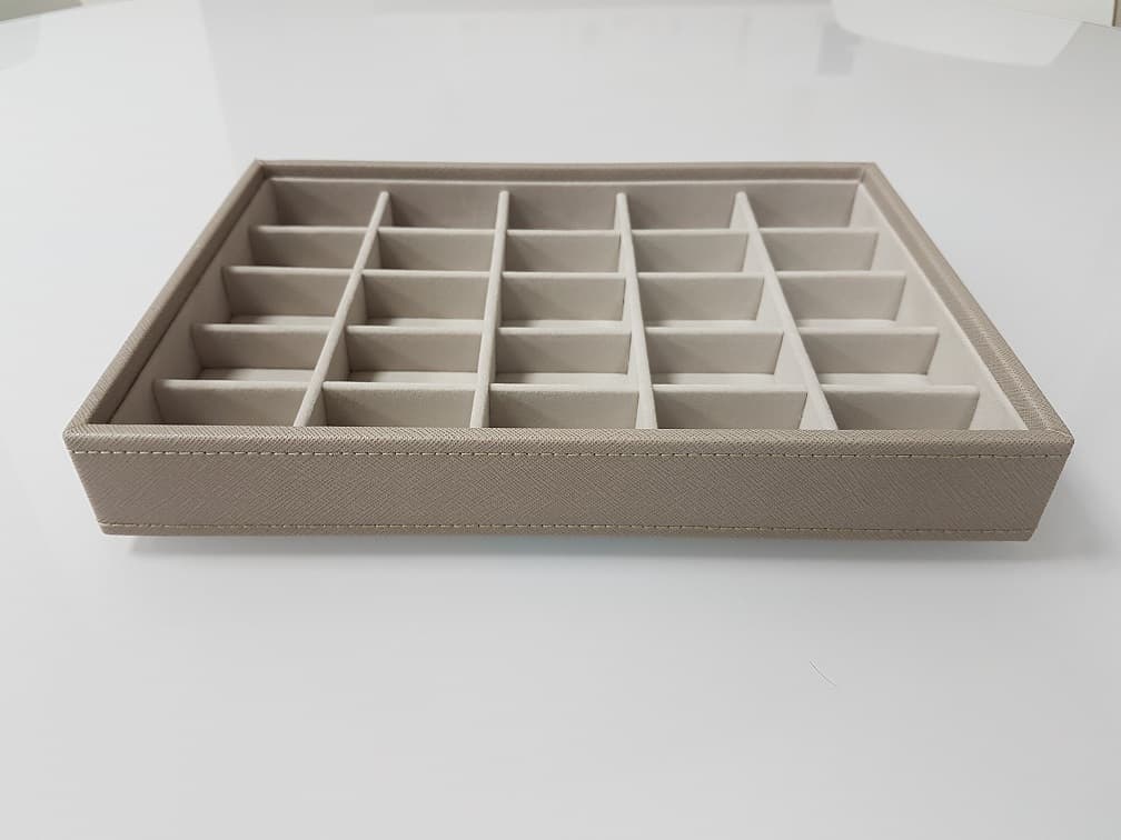 JEWELLERY DISPLAY BOX LAYER. MADE FROM MEDIUM DENSITY FIBREBOARD (MDF). CONSTRUCTION (52%), POLYESTER LINING (18%), POLYURETHANE OUTER SURFACE (10%), CARDBOARD (17%) AND SPONGE (3%). COMPLETE WITH INDIVIDUAL COMPARTMENTS SHAPED TO HOLD AND DISPLAY JEWELLERY. THE ESSENTIAL CHARACTER OF THE BOX IS IMPARTED BY THE MDF FRAME, WHICH PREDOMINATES IN WEIGHT, VALUE AND WHICH GIVES THE BOX ITS STRUCTURE AND FUNCTION. INCLUDES THE COMPANY LOGO ON THE INSIDE OF THE BOX.
