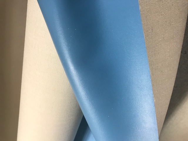 A WOVEN POLYESTER TEXTILE.  VISIBLY COATED ON ONE SIDE WITH A NON CELLULAR PVC PLASTIC COATING. ON A ROLL. SAMPLE SEEN GREY IN COLOUR