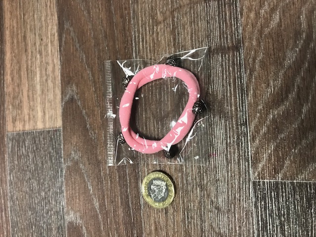 KNITTED POLYESTER TEXTILE HAIRBAND.  ELASTICED. DESIGNED TO HOLD THE HAIR IN THE STYLE OF A PONY TAIL. DECORATED WITH 5 SMALL APPLIED PLASTIC SHAMBALLA BALLS SPACED AROUND THE BAND. PACKED IN A PLASTIC BAG.