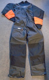 WOVEN DRYSUIT FOR UNISEX. ROUND NECK WITH NEOPRENE COLLAR WITH KNITTED TEXTILE ON OUTER SURFACE. WITH DOUBLE ZIP FASTENING FROM SHOULDER ACROSS THE FRONT. LONG SLEEVES WITH NEOPRENE CUFFS. HEMMED AT LEG ENDS. ELASTICATED AT BACK OF WAIST. WITH REINFORCEMENT PATCHES OF WOVEN FABRIC AT SEAT AND KNEES. WITH POCKET ON RIGHT THIGH FASTENED BY FLAP. WITH VARIOUS PRINTED LOGOS. MAIN FABRIC CONSTRUCTED OF TRILAMINATE FABRIC. OUTER WOVEN NYLON, INNER KNITTED TEXTILE WITH CENTRAL PLASTIC BONDING LAYER VISIBLE IN CROSS SECTION.