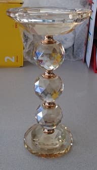 A 20CM TALL GLASS PILLAR CANDLESTICK WITH A RAISED RIDGE DESIGNED TO SECURELY HOLD A PILLAR CANDLE. THE CANDLE STICK IS MADE FROM GLASS.