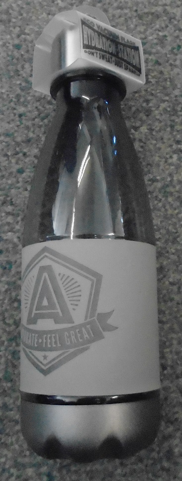 A TRANSPARENT PLASTIC BOTTLE OF POLYETHYLENE TEREPHTHALATE GLYCOL (PETG). IT IS COVERED ROUND THE LOWER HALF WITH A REMOVEABLE BAND OF A RUBBER-LIKE MATERIAL. THE BASE IS A SILVER COLOUR MADE OF A SEPARATE HARD PLASTIC. IT HAS A SCREW TOP MADE OF METAL. THE BOTTLE HOLDS APPROXIMATELY 500 ML.