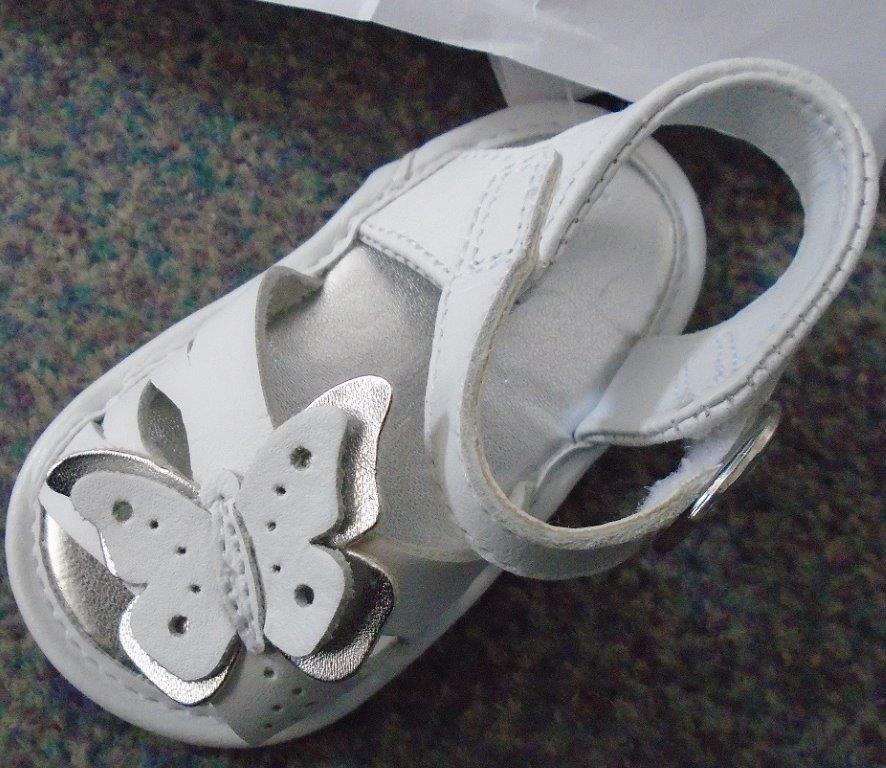 A GIRLS OPEN TOE SANDAL WITH UPPERS OF LEATHER AND OUTER SOLE OF TEXTILE MATERIAL WITH NON SLIP PU DOTS FOR GRIP AND BRAND INSCRIPTION - TEXTILE PREDOMINATES. THE VAMP IS MADE OF STRAPS. THE SANDAL IS WHITE IN COLOUR WITH A DECORATIVE BUTTERFLY ON THE TOP OF THE VAMP. IT HAS A VELCRO FASTENING AROUND THE ANKLE AND IS LESS THAN 24CMS IN LENGTH.