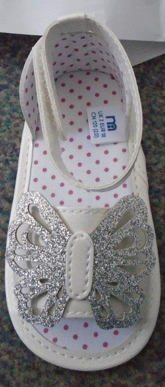 A BABY GIRLS SANDAL WITH UPPERS OF PLASTIC WITH OUTER SOLE  OF TEXTILE MATERIAL WITH PLASTIC BUTTERFLIES FOR GRIP - TEXTILE PREDOMINATES.
WHITE IN COLOUR.THE SANDAL HAS A DECORATIVE BUTTERFLY AT THE TOP OF THE VAMP.  AN OPEN TOE SANDAL WITH A VELCRO STRAP AROUND THE ANKLE.
THE SANDAL IS LESS THAN 24 CMS.