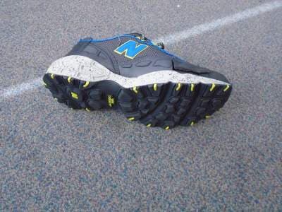 MENS TRAINER WITH UPPERS OF TEXTILE  PLASTIC AND LEATHER.THE TEXTILE IS THE PREDOMINANT MATERIAL. A RUBBER OUTER SOLE.THE INSOLE IS REMOVABLE.THE TRAINER HAS A  GREY LEATHER TOE CAP AND A BLUE DECORATIVE TRIM AND AN APPLIED DECORATIVE LETTER N. THERE ARE YELLOW TEXTILE EYELETS AND PATTERNED GREY AND YELLOW LACES.