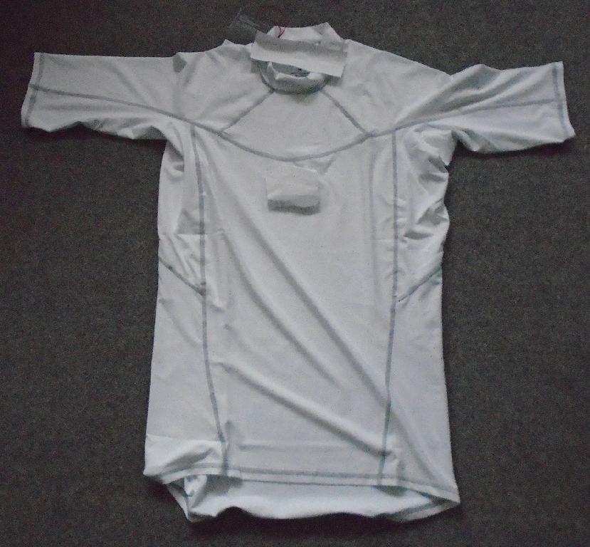 A WHITE KNITTED T-SHIRT. REACHING DOWN TO BELOW THE WAIST. WITH A ROUND NECK WITHOUT AN OPENING. WITH A 3CM DEEP BAND AROUND THE NECKLINE. WITH SHORT SLEEVES. THE GARMENT IS HEMMED AT THE SLEEVE ENDS AND AROUND THE BASE. A 4 WAY STRETCH FABRIC, WITH FLAT LOCKED SEAMS FOR COMFORT. WITH THE COMPANY LOGO PRINTED IN THE MIDDLE OF THE CHEST. LEFT SHOULDER THERE IS PRINTED WORDING. THE GARMENT IS MADE OF 86% POLYESTER AND 14% ELASTANE. PACKAGED IN A CLEAR PLASTIC BAG WITH A PRINTED BARCODE, GARMENT DESCRIPTION, PRODUCT CODE AND SIZE.