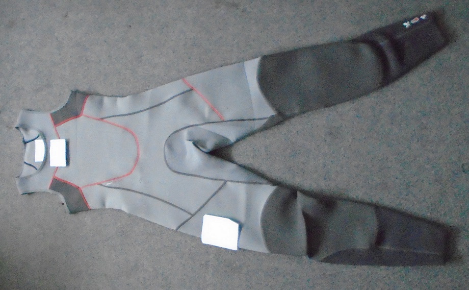 A SKIFF SUIT. AN ALL IN ONE GARMENT. REACHING FROM THE SHOULDERS TO THE ANKLES. ROUND NECK, WITHOUT SLEEVES, AND NO FASTENING. A KNITTED UNISEX ITEM MADE OF A RUBBERISED FABRIC, 90% NEOPRENE AND 10% NYLON. LOGOS ON UPPER LEFT AND ON RIGHT LEG. FOR USE IN SAILING