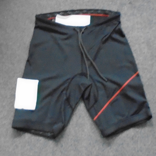 UNISEX KNITTED SHORTS, WITH AN ELASTICATED WAIST WITHOUT AN OPENING, WITH A DRAWSTRING TIE. THE SHORTS REACH DOWN TO THE KNEE. WITH GRIPPER ELASTIC AT THE LEG ENDS TO HELP KEEP THE SHORTS SECURE AND PREVENT WATER FLUSH. THE SHORTS ARE MADE OF 88% NYLON AND 12% ELASTANE, WITH CONTOURED PADDING ON THE SEAT AND BACK OF THE THIGHS FOR FAST DRAINAGE AND VENTILATED COMFORT. THE SEAT PANELS ARE ABRASION RESISTANT. THE PANELS ARE MADE OF 90% NEOPRENE AND 10% ELASTANE COVERED ON BOTH SIDES WITH A TEXTILE FABRIC. WITH A PRINTED COMPANY LOGO ON THE RIGHT LEG.  PACKAGED IN A CLEAR PLASTIC BAG WITH A PRINTED BARCODE, GARMENT DESCRIPTION, PRODUCT CODE AND SIZE.