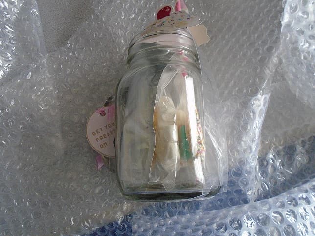 A CLEAR GLASS JAR MEASURING APPROX 14CMS IN HEIGHT AND 6CM IN DIAMETER WITH HANDLE. WITH INSCRIPTION ON THE SIDE. WITH THREAD AT TOP OF JAR. DESIGNED FOR USE TO MAKE A SUNDAE, ACCOMPANIED WITH THREE SUGAR COOKIES, A 25G VANILLA MILKSHAKE POWDER, 10G BAG OF SPRINKLES, 10G BAG OF MARSHMALLOWS, 25G BAG OF JELLYBEANS. ALL EDIBLE ITEMS ARE CONSIDERED TO BE NEGLIGIBLE FOR SINGLE USE TO MAKE THE SUNDAE. WITH A PAPER STRAW. PACKAGED WITH A PLASTIC SURROUND HOLDING THE ITEMS IN PLACE FOR RETAIL SALE. WITH CARDBOARD PICTURE OF A SUNDAE AND A PINK BOW ON TOP.
