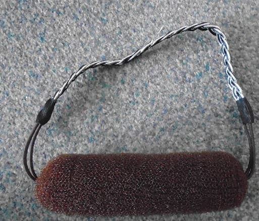 HAIR STYLING TOOL.
NYLON MESH ROLL WITH ELASTIC ON EITHER SIDE WITH A THREE BRAID BAND CONSISTING OF TWO SILVER AND ONE BLACK, PLAITED TOGETHER TO FORM A DECORATIVE HEADBAND MADE FROM POLYESTER.
THIS CAN BE USED TO HOLD THE HAIR BACK AND TO ASSIST WITH PUTTING HAIR UP.