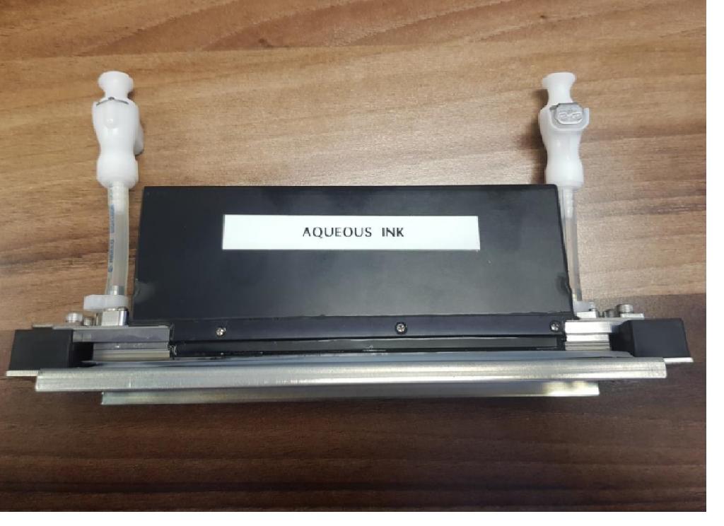 INKJET PRINTHEAD FOR USE IN HIGH CAPACITY PRINTING APPLICATIONS SUCH AS LABEL PRINTING USING AN ULTRA VIIOLET INK. FOUR INCH WIDE PRINT HEAD CONTAINS MORE THAN 2500 JETTING ELEMENTS TO PROVIDE A RESOLUTION OF BETWEEN 150 DPI AND 1200 DPI. THE PRINT HEAD WORKS BY PIEZO ELECTRIC VIBRATION OF THE RELEVANT NOZZLES WHICH CAUSES A DROP OF INK TO BE RELEASED. THE PRINT HEAD IS MECHANICALLY ALIGNED WITH THE PRINTER AND SCREWED INTO POSITION. THE PRINTING FACE IS MADE FROM STAINLESS STEEL, WITH A METAL FRAME HOUSING A NUMBER OF CIRCUIT BOARDS REQUIRED FOR OPERATION OF THE PRINT HEAD. TWO PLASTIC TUBES ARE ATTACHED; ONE IS TO SUPPLY THE INK OTHER FOR CLEANING PURPOSES.