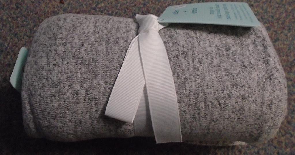 A KNITTED BLANKET PRIMARILY USED FOR BABIES.
THE BLANKET IS MADE OF VISCOSE, POLYESTER AND ELASTANE JERSEY, KNITTED FABRIC. COLOURED DARK AND LIGHT GREY MOTTLED. COVERSTITCHED AND STITCHED FOLDED HEMS ON ALL FOUR SIDES.
IT IS DESIGNED FOR SEVERAL USES, E.G., SWADDLING, TO WRAP A BABY/ CHILD. A NURSING COVER, AS A BLANKET.
PACKAGED AND SEALED IN A POLYTHENE BAG.