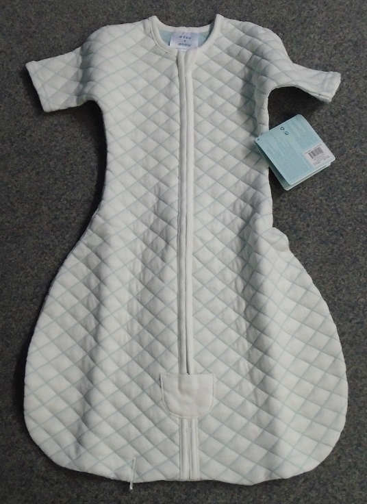 THE GARMENT APPEARS TO BE CLOSE FITTING TO THE BODY, WITH LONG SLEEVES. THE ROUNDED BOTTOM OF THE GARMENT IS STITCHED TOGETHER TO ENCLOSE THE LOWER HALF OF THE CHILDS BODY. 

A ZIP IS SITUATED IN THE FRONT CENTRE OF THE GARMENT. THE ZIP AND NECK EDGES ARE BOUND WITH WHITE/CREAM BINDING SIMILAR TO BIAS BINDING. THE SLEEVE ARE HEMMED. 

THE GARMENT IS WHITE/CREAM IN COLOUR WITH PALE GREEN STITCHING FORMING A QUILTED DIAMOND PATTERN.  

THE GARMENT IS PACKAGED ON A CARDBOARD HANGER. A MANUFACTURERS LABEL IS ATTACHED WITH A PLASTIC  GARMENT TAG AND PRESENTED IN A PLASTIC BAG FOR RETAIL S