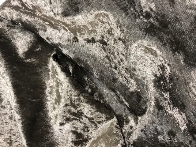 CRUSHED VELVET FABRIC. MADE UP OF TWO LAYERS, THE TOP LAYER IS THE ESSENTIAL CHARACTER CONSISTING OF A GREY KNITTED POLYESTER PILE FABRIC, BONDED TOGETHER WITH A BOTTOM LAYER OF WHITE WOVEN MESH FABRIC.THE BONDING ADHESIVE CAN NOT BE SEEN IN CROSS SECTION. CAN BE USED FOR CUSHION COVERS, CURTAINS OR DRESSMAKING. IT IS A LOOSE FABRIC THAT COMES IN A ROLL.