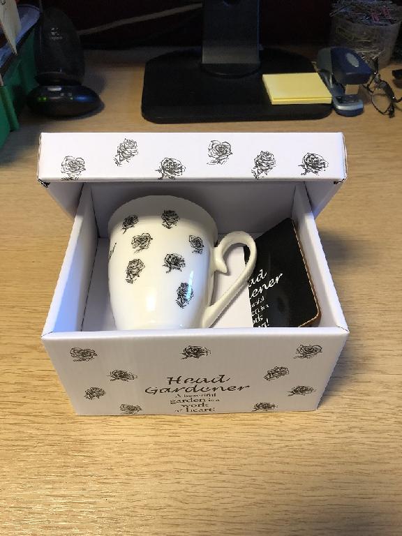 BOX MADE FROM CORRUGATED CARDBOARD. IT IS WHITE IN COLOUR WITH BLACK ROSES ON WITH THE WORDS - HEAD GARDENER A BEAUTIFUL GARDEN IS A WORK OF HEART.
IT IS 16.5 X 17CM WIDE AND 9CM DEEP. THE LID IS 18CM X 15CM AND 9CM DEEP. BOTH THE BOX AND LID ARE DOUBLE FOLDED. 
THE BOX IS PART OF A SET CONTAINING  A MATCHING MUG AND MDF COASTER WHICH HAS BEEN CLASSIFIED SEPERATELY.