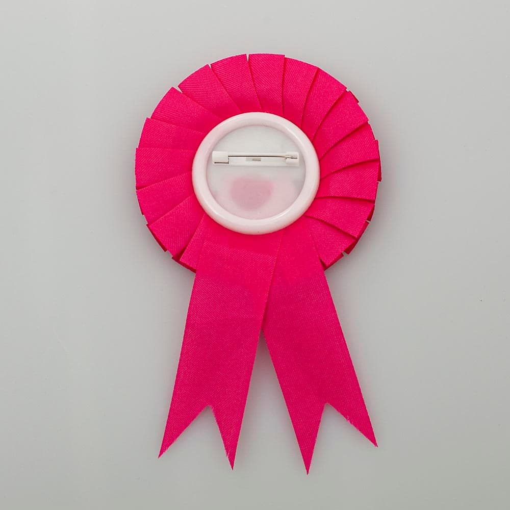 ROSETTE BIRTHDAY BADGE WITH PIN. FINISHED PRODUCT MEASURES 80 X 145MM.PRODUCT HAS A ROUND TIN FRONT WITH THE WORDS "BIRTHDAY GIRL" PRINTED ON IT WITH A PLASTIC BACKING WITH ATTACHED SAFETY PIN OF STAINLESS STEEL. BADGE IS DECORATED WITH PINK SATIN RIBBON WHICH GOES ALL THE WAY AROUND THE BADGE AND THERE ARE TWO TAILS OF RIBBON UNDERNEATH. FINISHED PRODUCT IS MOUNTED ONTO A FLAT PIECE OF CARD FOR RETAIL SALE.