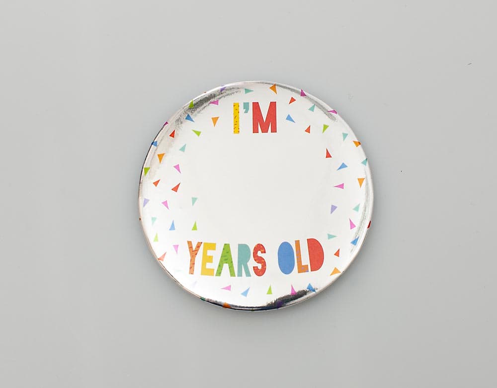 THE ITEM IS A ROUND BADGE WITH 'I'M  YEARS OLD' PRINTED ON IT. THE PRODUCT COMES WITH NUMBER STICKERS TO ALLOW PERSONALISATION. THE BADGE IS MADE OF TIN AND IT IS MOUNTED ONTO A 1.5MM THICK LINED GREYBOARD ATTACHED TO WHICH IS A PLASTIC CLIP SO BADGE CAN BE ATTACHED TO CLOTHING. THE FRONT HAS A COVER OF POLYETHYLENE FOIL WITH METALLIC PAINT APPLIED TO IT.