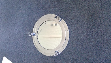A MIRROR IN THE STYLE OF A SHIPS PORTHOLE.

THE MIRROR IS INTENDED TO BE FIXED TO A WALL AS IT DOES NOT APPEAR TO BE FREESTANDING. THE FRAME OF THE MIRROR IS MADE OF ALUMINIUM AND FINISHED WITH NICKEL PLATING, GIVING IT A POLISHED SILVER APPEARANCE. THE FRAME IS IN TWO PARTS, AN OUTER CIRCLE WHICH HAS A RAISED PATTERN ON THE OUTER EDGE THAT APPEARS TO BE A RIVET DECORATION AND AN INNER CIRCULAR FRAME HINGED TO THE OUTER CIRCLE OF THE FRAME ENABLING THE INNER FRAME TO OPEN AND CLOSE,  GIVING IT THE APPEARANCE OF A PORTHOLE IN A SHIP.  
THE OUTER CIRCLE HOLDS THE GLASS MIRROR IN PLACE BY EIGHT SPRING CLIPS, A DARK COLOURED CORD IS SITUATED AROUND THE OUTSIDE FOR DECORATION OR TO HIDE THE EDGES OF THE MIRROR. THE OUTER FRAME HAS TWO TRIANGULAR LOCKING BOLTS WHICH APPEAR TO SECURE THE INNER FRAME IN A LOCKED POSITION.  
THERE ARE NO ELECTRICAL COMPONENTS CONTAINED OR ATTACHED.
