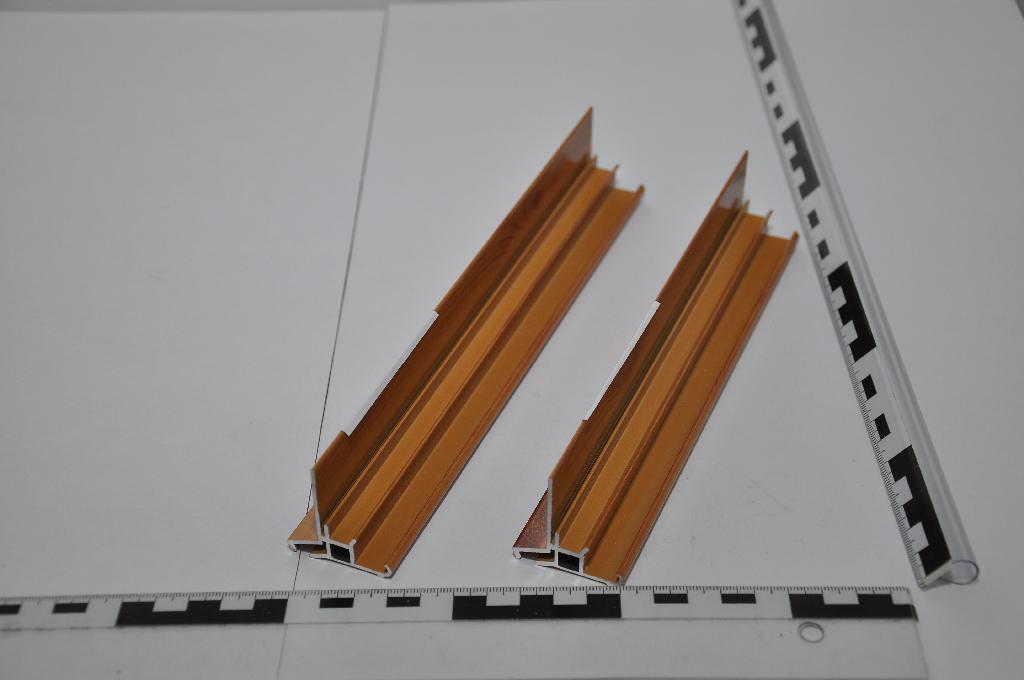 A termék megnevezése „vakolósín”. A minta 38,7 mm szélességű és 36,6 mm vastagságú, 6 m hosszúságú, szinterezett (porfestett), faerezetű és világosbarnára színezett profil, szerkezetben való felhasználásra előkészítve.
A redőnyrendszerek elrejtésénél a vakolás megkönnyítését szolgálja. A redőnytokkal együtt felszerelhető az ablaktok külső részére. A vakolósín segítségével a fal szigetelése és a vakolat elsimítása könnyebben elvégezhető a tok sérülése nélkül, a termék tartja a szigetelést és a vakolatot.
Fő tömegében alumíniumból készült, Mg tartalma 0,1456 %, alumíniumötvözet. A gazdálkodó adatközlése alapján 6063-T5-ös szabványnak megfelelő alumíniumötvözet, extrudálással került kialakításra, festhető termék.