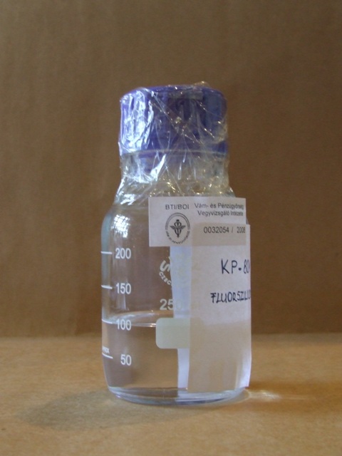 KP-801M fluoroszilikon bevonószer Csomagolás: A minta átlátszó 300ml-es folyadéküvegben, felcimkézve érkezett. A mintásüveg kék kupakját ragasztószalaggal zárták körbe. Vizsgálati eredmények: Érzékszervi vizsgálat: Színtelen víztiszta kis viszkozitású, jellegzetes szagú folyadék.  Szárazanyag: 3,0 m/m % FT-IR vizsgálat (eredeti minta):	FT-IR alapján m-xilol-hexafluorid mutatható ki. FT-IR vizsgálat (szárazanyag): A szárazanyag fluor-polimer származék. Az elvégzett vizsgálatok és a benyújtott nyilatkozatok alapján a minta 3,0 m/m % fluor-polimer bevonó anyagot tartalmaz, 97 m/m % m-xilol-hexafluorid-ban oldva. A minta megfelel a gyártó által megadott összetételnek.