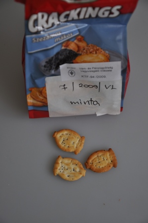 CRACKINGS SZEZÁMOS - MÁKOS ízesített biscuits. A minta eredeti kiszerelésű, a kiskereskedelmi forgalom számára kiszerelt kék-piros alapszínű PP zacskóban, két végén légmentesen lezárva, sértetlenül érkezett vizsgálatra. Nettó tömeg: 125 g. Vizsgálati eredmények: Érzékszervi vizsgálat: kb. 3 cm nagyságú, aranybarnára sütött, felületén sóval megszórt, tésztájában szezámmagot és mákot tartalmazó, olajos tapintású, sós ízű, laza szerkezetű, mákgubó alakú keksz. Laboratóriumi vizsgálatok: Cukortartalom (HPLC): glükóz: 0,3 m/m%, laktóz: 0,5 m/m%, szacharóz: 3,3 m/m%, maltóz: 0,8 m/m%; Szárazanyag-tartalom (MSZ 9433-83): 99,7 m/m%; Zsírtartalom (MSZ 9433-83): 22,7 m/m%.