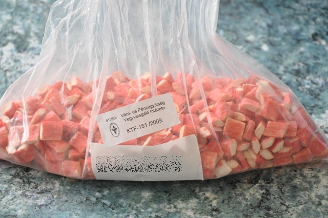 Surimi készítmény. A jogosult nyilatkozata alapján a termék az ún. „instant száraztészta levesporral” késztermékben kerül felhasználásra. Vizsgálati eredmények: Érzékszervi vizsgálat: 1 mm vastagságú lapból feltekert, 0,5 cm vastagságúra ellapított, 1 cm szélességűre darabolt, törtfehér színű, szivacsos állagú, halas illatú és ízű, kissé sós, kemény, ropogós, külsején piros, vágási felületén törtfehér színű készítmény. Laboratóriumi vizsgálat: Keményítőtartalom (4154/87/EGK, 900/2008/EK): 28 m/m%.