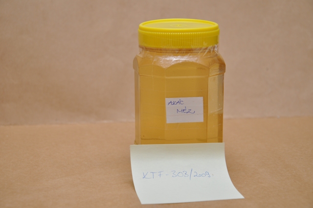 A minta sárga csavaros, műanyag fedelű, 250 ml-es, nyolcszögletű műanyag edényben érkezett vizsgálatra. A doboz oldalára ragasztott fehér címkén a minta neve: Akácméz olvasható.
Vizsgálati eredmények: Érzékszervi vizsgálat: aranysárga színű, akácmézre jellemző illatú és ízű sűrűn folyó méz, kevés sárga és minimális világos barna színű szilárd darabokkal. Laboratóriumi vizsgálatok: Cukortartalom (HPLC): fruktóz: 43,4 m/m%, glükóz: 26,9 m/m%, szacharóz: 2,9 m/m%, maltóz: 0,6 m/m%. Eredetvizsgálat (EA-IRMS): 13C/12C arány alapján a minta izo-cukrot nem tartalmaz. A minta mért cukortartalma a csatolt MÉK 1-3-2001/110 Méz előírásnak megfelel. Az elvégzett érzékszervi és laboratóriumi vizsgálatok valamint a csatolt dokumentumok alapján a minta természetes méz.